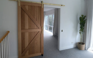 Barn door with brushed gold hardware installed on plasterboard wall in Australian home