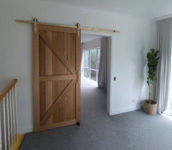 Barn door with brushed gold hardware installed on plasterboard wall in Australian home