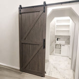 A dark brown wood sliding barn door with black metal hardware, shown partially open in a modern bathroom setting.